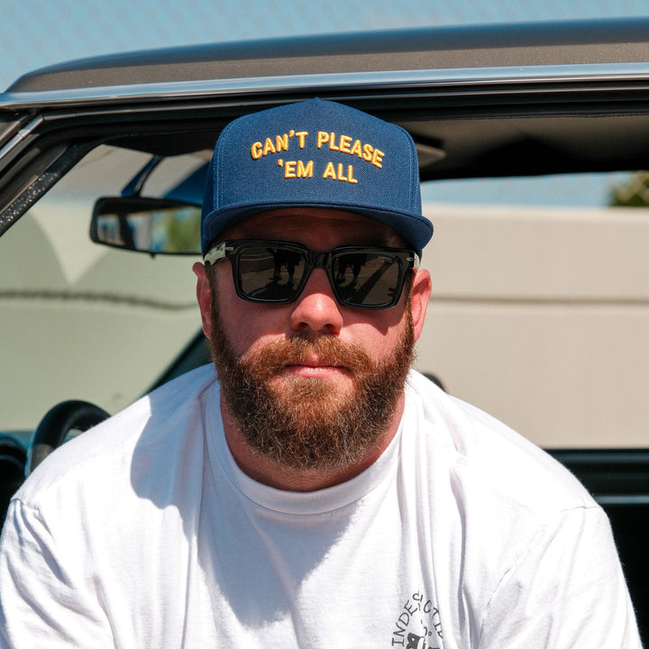 A man with a beard wearing a blue cap that says &