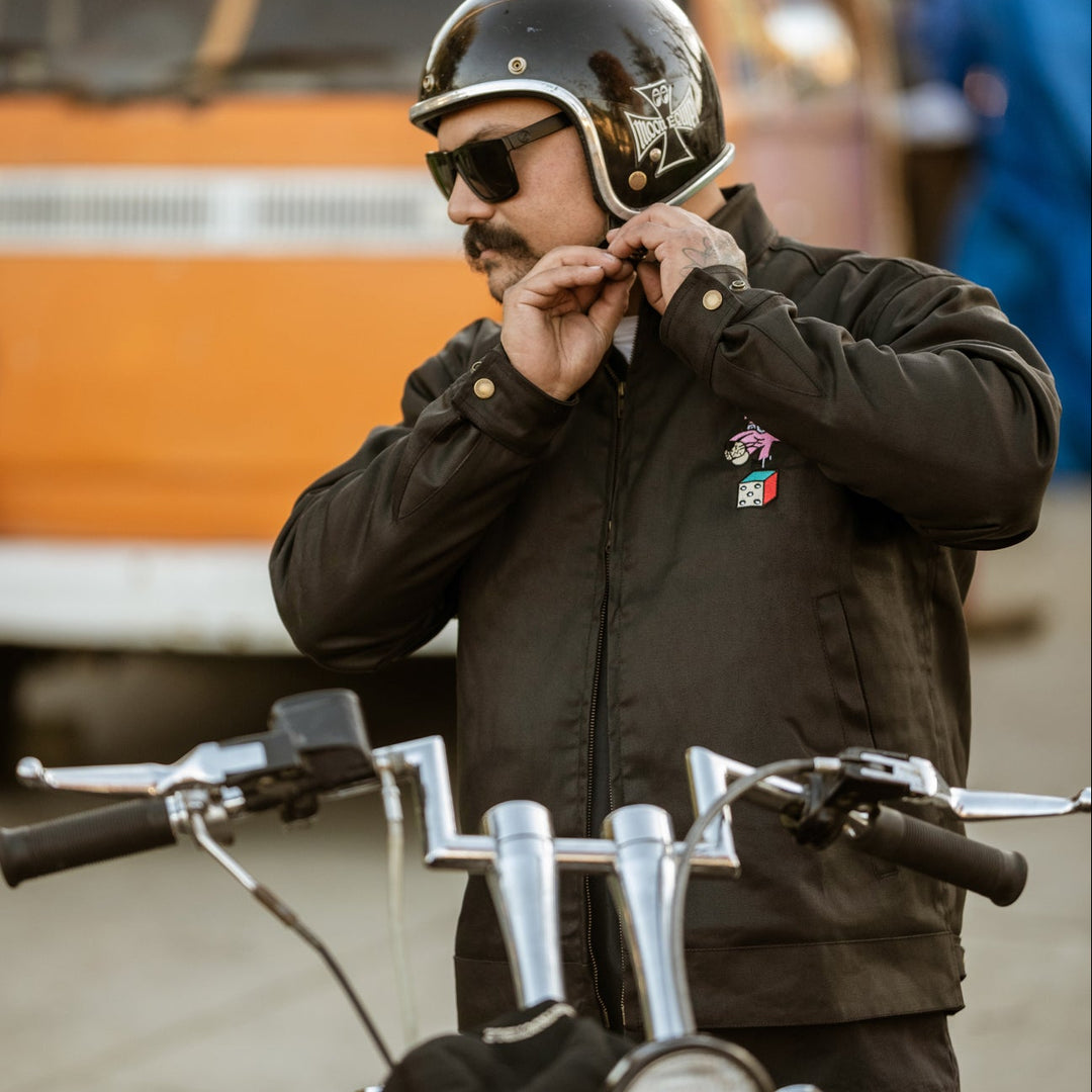 Man adjusting his helmet in front of a motorcycle with a blurred background