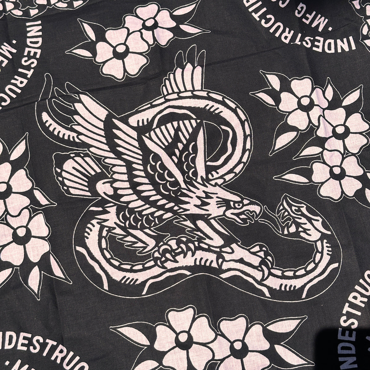 Black fabric with white tattoo-style designs of a swan and flowers, featuring 'Indestructible Mfg Co.' branding.