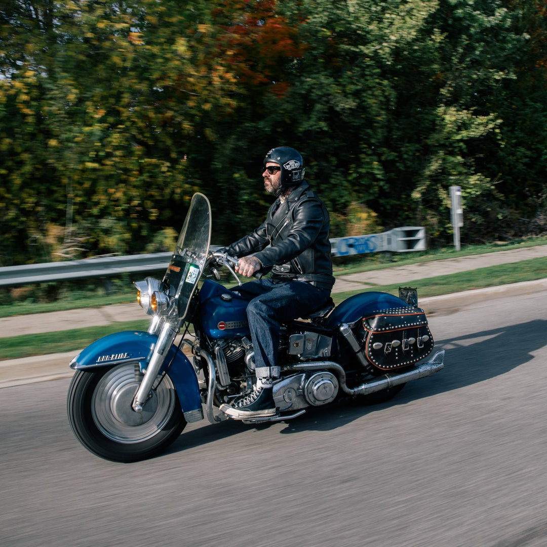 Person riding a motorcycle on a road with trees in the background